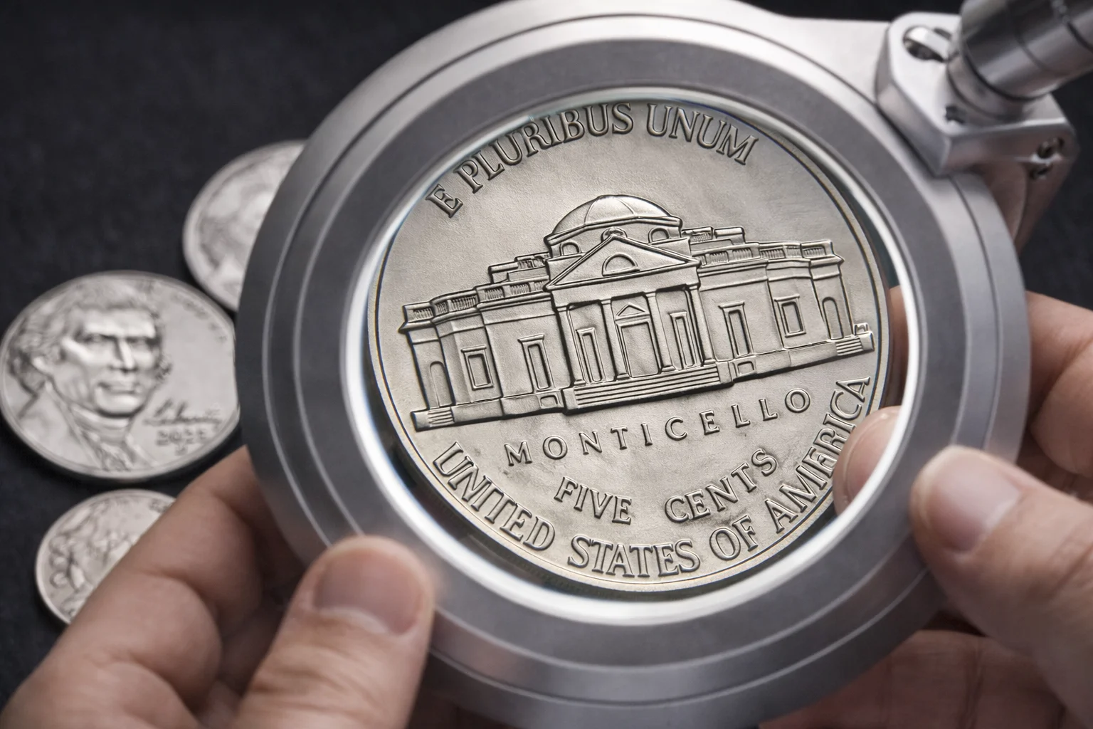 ollector examining 2025 Jefferson nickel reverse under magnifier.